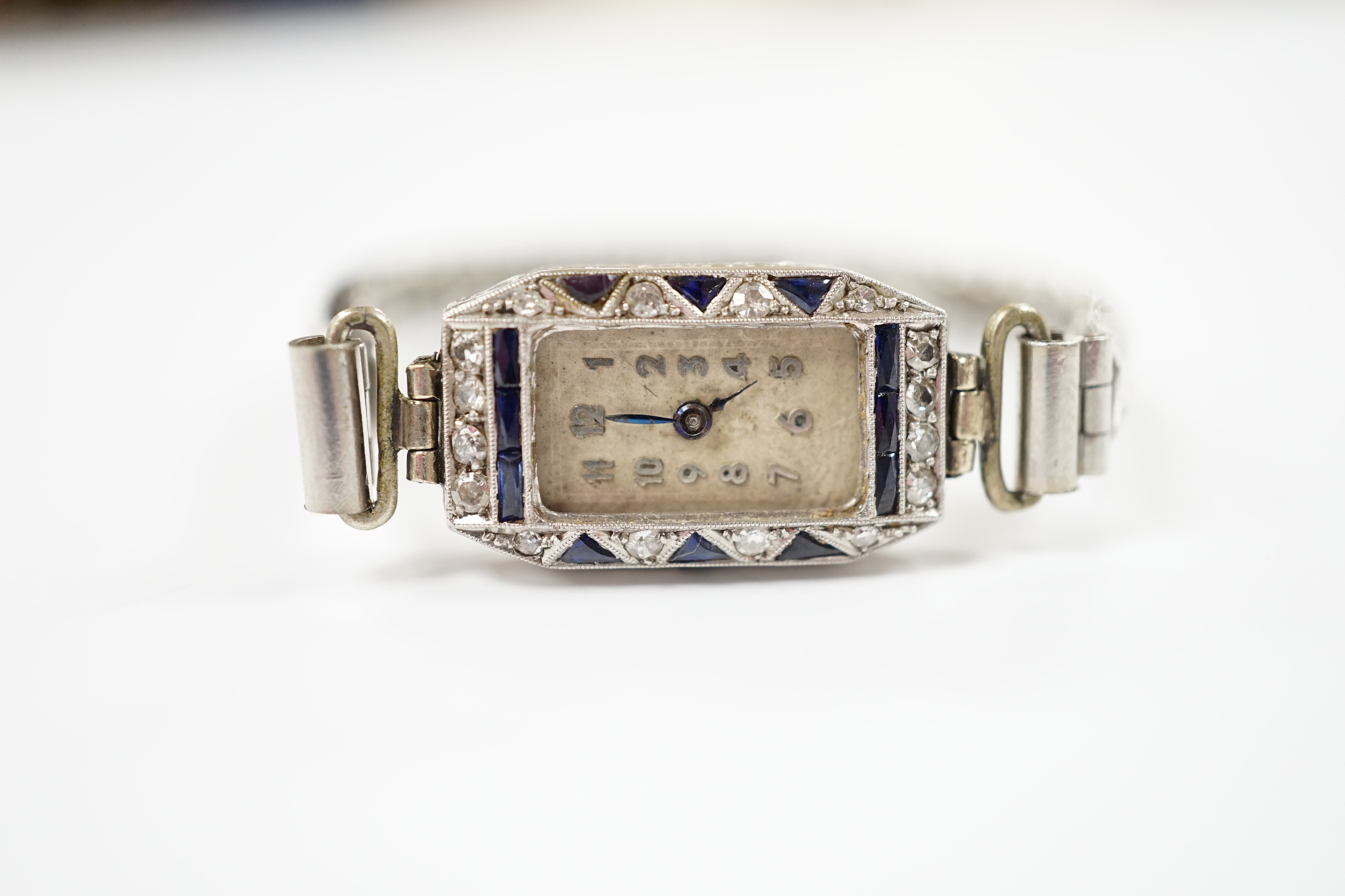 A lady's 1930's white metal (stamped platina), diamond and sapphire set manual wind cocktail watch (no glass or winding crown), on a stainless steel expanding bracelet.